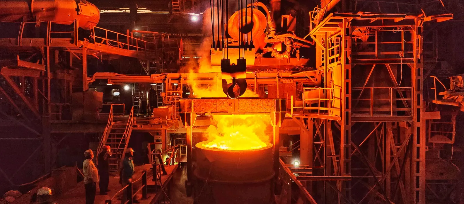 Industrial furnace melting and pouring molten metal during steel production.